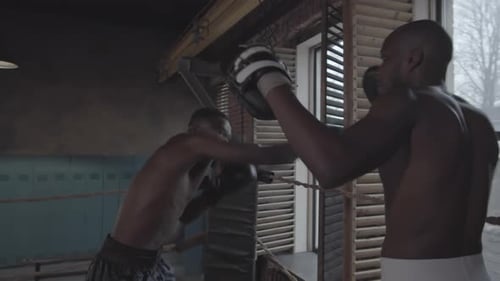 Amateur Afro-American Boxer Training with Coach at Dingy Fight Club