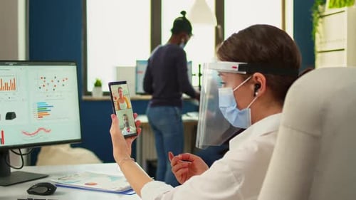 Woman in Office Attends Virtual Meeting on Smartphone