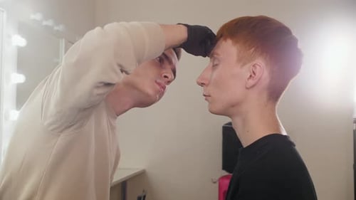 Attractive Man Brow Master Drawing Guiding Lines on the Eyebrows of His Male Client in Backstage