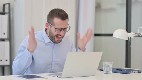 Man Working at Desk Celebrates Success