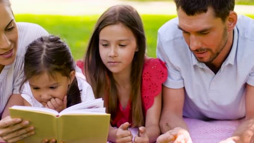 Family Reading Book on Picnic in Summer Park