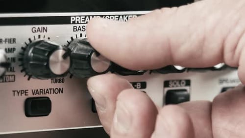 Musician's hand sets up the levels of a guitar preamp multi effect, close up.