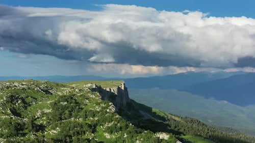 Aerial View of Mountain Cliffside Under Cloudy Skies