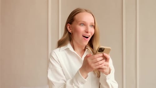 Woman Looks at Phone and Reacts with Excitement