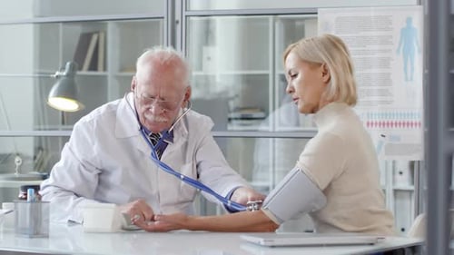 Doctor Checks Blood Pressure of Patient in Office