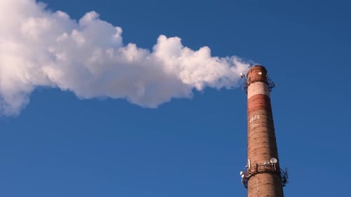 Industrial Chimney Emitting White Smoke Against Blue Sky