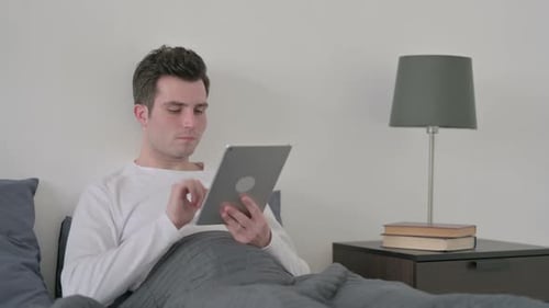 Young Adult Using Tablet in Bed