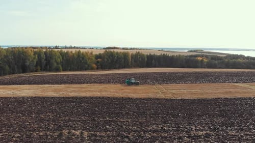 An Autumn Landscape of Fields, Sky and a Village - Tractors Plows the Field