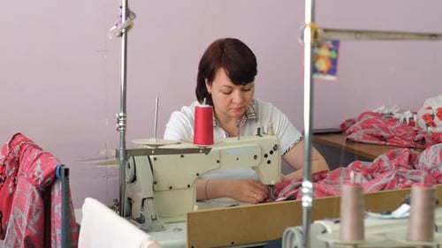Woman Works Sewing Machine in Bright Factory Setting