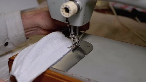 Hands Using a Sewing Machine to Stitch Cloth