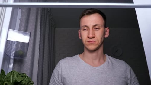 Sleepy Man Takes and Bites Delicious Green Apple From Fridge