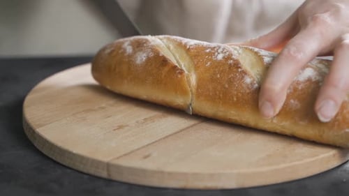 Slicing Baguette on Table. Baguette Traditional French Bread on the Table Cutting Close-up.