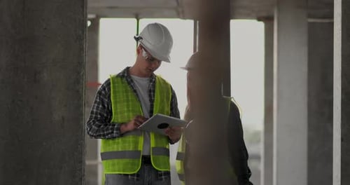 Construction Workers Discussing Plans on Tablet in Building