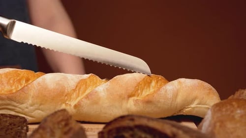 Slicing Crusty Baguette Bread Loaf with Knife