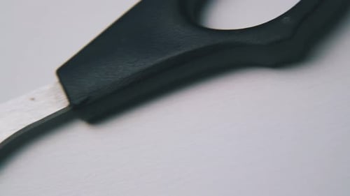 Motion Along Scissors with Black Handles on White Surface