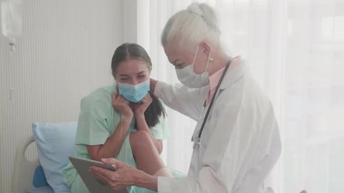 Doctor Shows Tablet to Patient in Hospital Bed