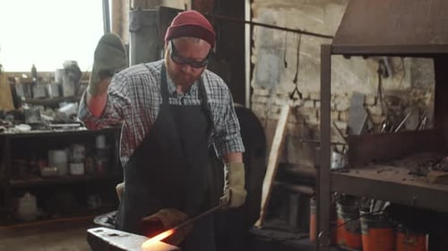 Blacksmith Shaping Hot Metal Rod in Workshop