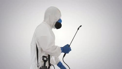 Mann in einem Gefahrgutanzug geht und besprüht mit einem Desinfektionsmittel auf Gradientenhintergrund