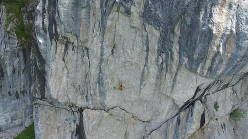 Aerial drone view of a man rock climbing up a mountain.