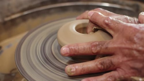 Potter utilise deux mains pour façonner le futur produit en argile avec le tour de potier