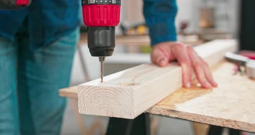 Adult Drilling Holes in a Wooden Board