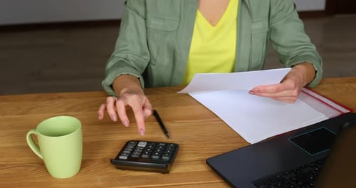 Woman Calculating Finances at Home on Wooden Desk