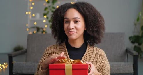 Smiling Woman Offers Red Gift with Gold Ribbon