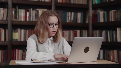 Woman Studying in Library Closes Laptop