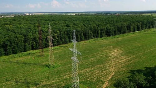 Transmission lines near green forest. High voltage electric line in the field.