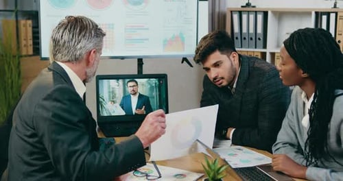 El equipo de negocios explica el informe con un gráfico a su barbudo jefe de empresa durante un chat de Vídeo en línea