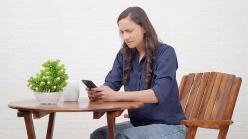 Woman Typing on Smartphone at Table