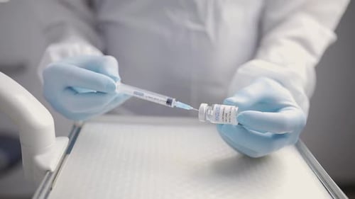 Crop doctor filling syringe with drug in hospital