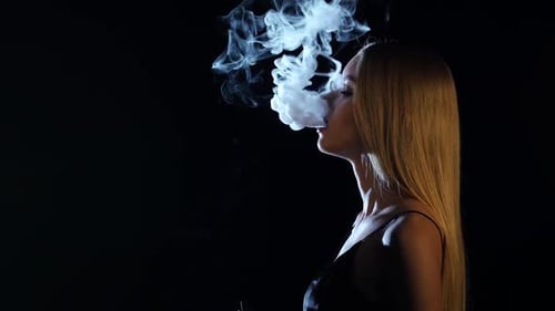 Fille d'une beaut extraordinaire fume une cigarette lectronique, fond noir, vue de ct Fille d'une beaut extraordinaire fume une cigarette lectronique, fond noir, vue de ct
