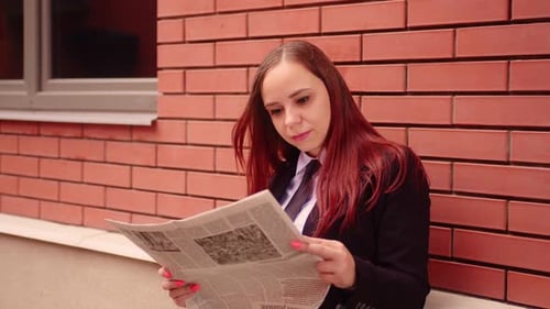 Young Woman Reading Newspaper on Street