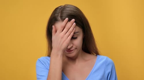 Closeup Portrait of Woman Putting Hand on Face with Tired Sad Headache Symptoms Isolated on Orange