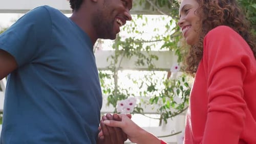 Torso de hombre birracial feliz proponiendo matrimonio a mujer birracial con anillo