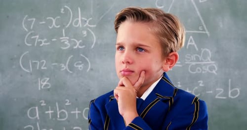 Young Boy Thinking in Front of Chalkboard