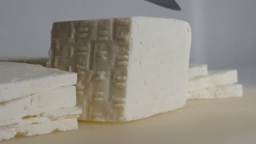 Cheese Block Being Sliced into Portions