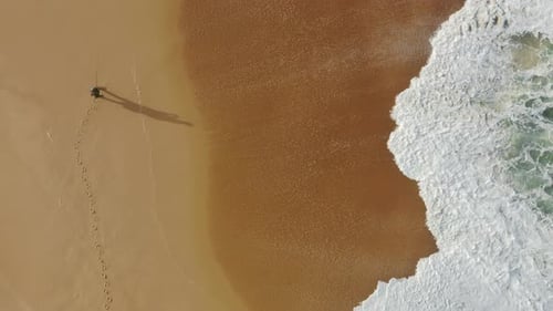 Lone Figure Walking on a Sandy Beach From Above