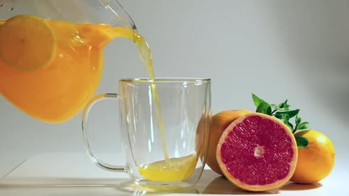 Fresh Orange Juice Poured Into Glass With Citrus Fruit