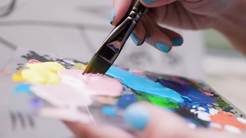 Woman artist working on canvas paint while mixing acrylic painting in palette inside art studio