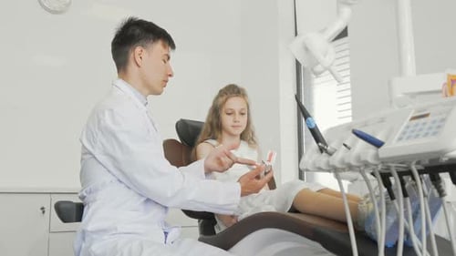 Little Girl Talking To Her Dentist Sitting in Dental Chair Ready for Teeth Checkup