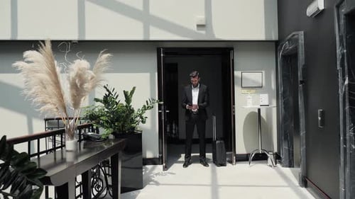Attractive Business Man Standing in Hotel Corridor Using Mobile Phone App