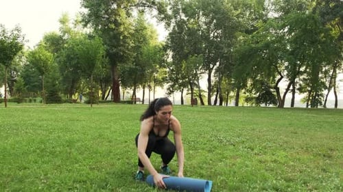 Woman Unrolls Yoga Mat in Green Park
