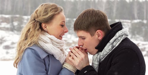 Affectionate Couple Warming Hands in Snowy Winter