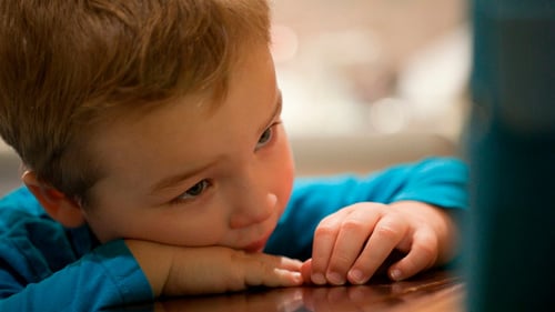 Child Resting Head on Hands at Table