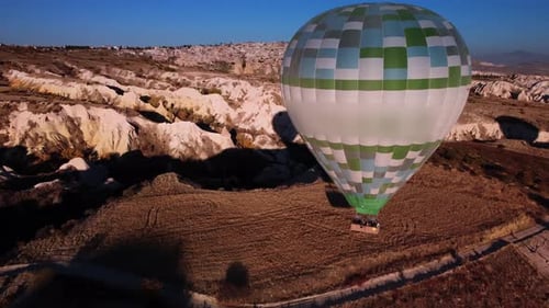 Aerial View of Hot Air Balloon with Tourists in Basket Landing on the Ground at Cappadocia Valley