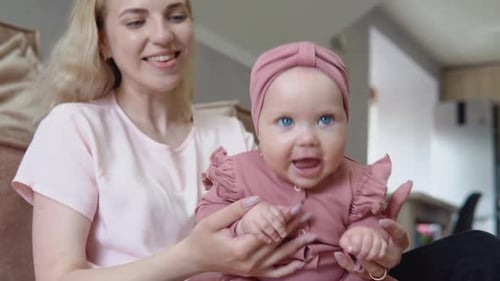 Happy Woman Holding Adorable Infant Smiling at Home