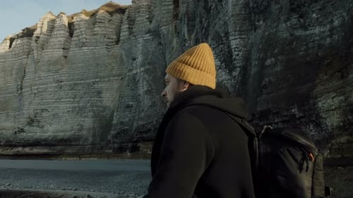 Camera Moves Around Happy Male Tourist Exploring Epic Sunny Rocky Beach, Looking for Inspiration