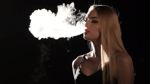 Blonde Woman Exhaling Thick Vape Smoke in Dark Studio Blonde Woman Exhaling Thick Vape Smoke in Dark Studio
